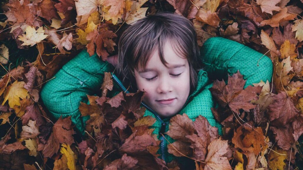 Στεναχωρημένο παιδάκι μέσα σε φύλλα. Πένθος στα παιδιά